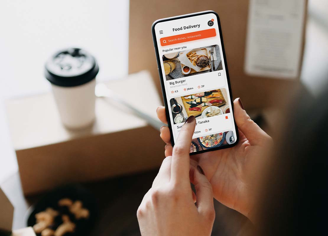 Mujer revisa una app de un restaurante y verifica su pedido de comida que está frente a ella