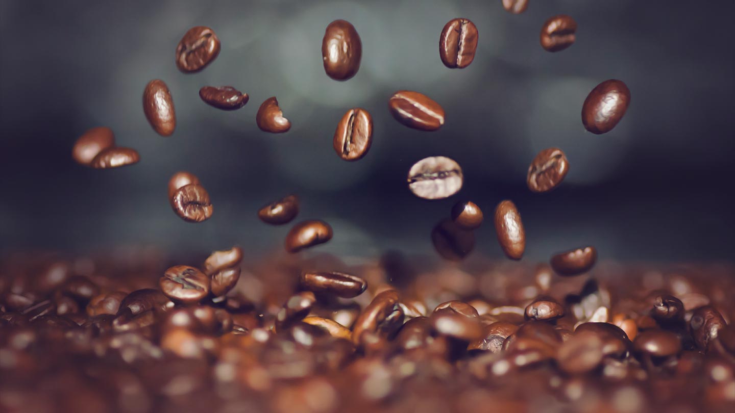 Sobre una pila de granos de café tostado, otros van cayendo