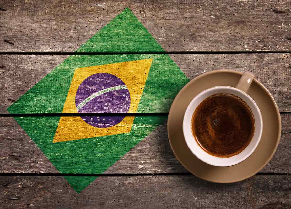 Sobre una tabla está el dibujo de la bandera de Brasil y al lado una taza de café
