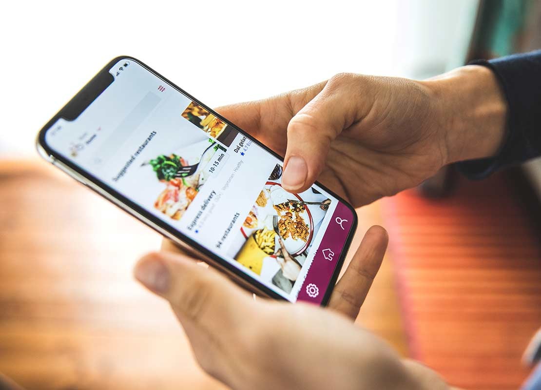 Manos sostienen un celular en el que se muestra el menú digital de un negocio de food service