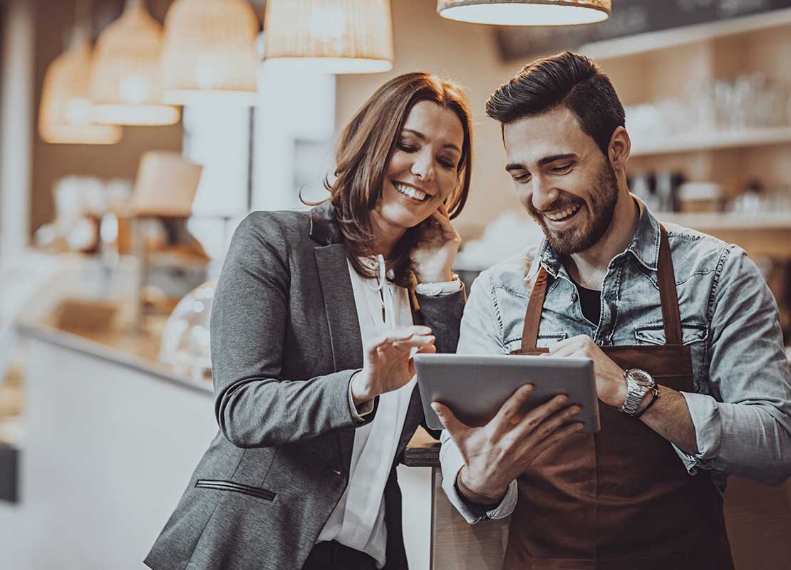 Dueña y barista de una cafetería revisan un menú digital en una tablet