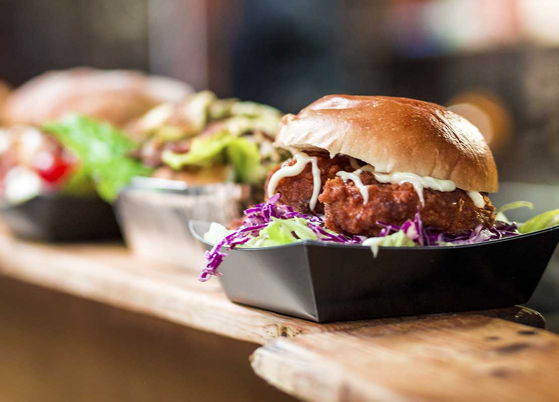 Hamburguesas servidas en un recipiente sobre la barra de un negocio gastronómico en un festival