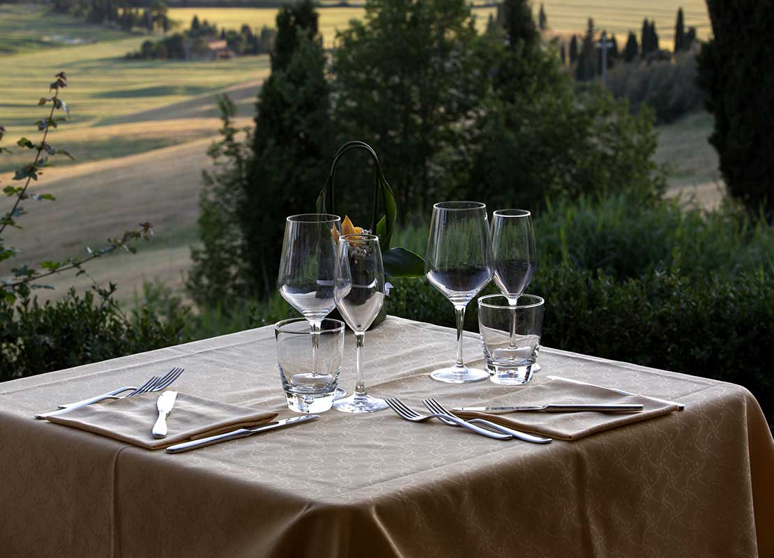 Al aire libre, mesa puesta con copas, servilletas, vasos y cubiertos