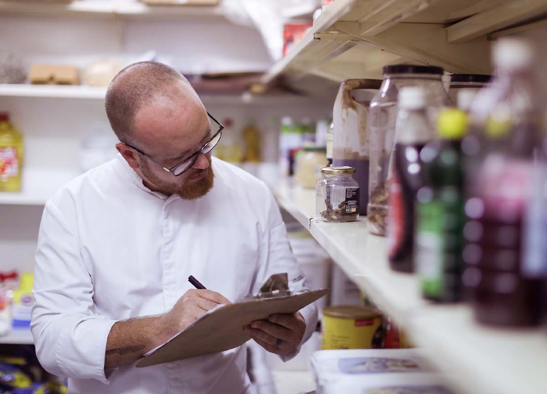 Chef ejecutivo en el almacén de un restaurante revisa y hace inventario de los ingredientes e insumos