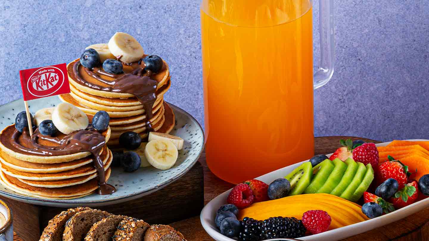 Desayuno con KITKAT® servido en diferentes platos, tazas, vasos y otras piezas de una vajilla