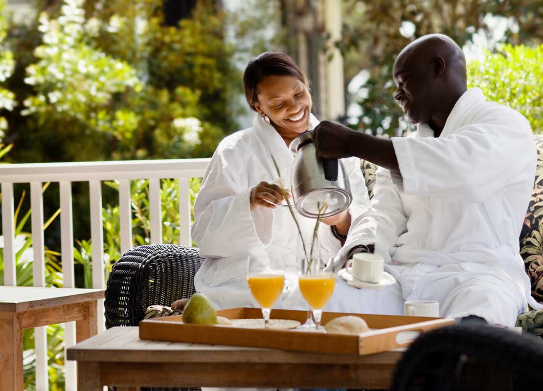 Dos huéspedes toman desayuno con jugo y café sentados a la mesa en el balcón de un hotel