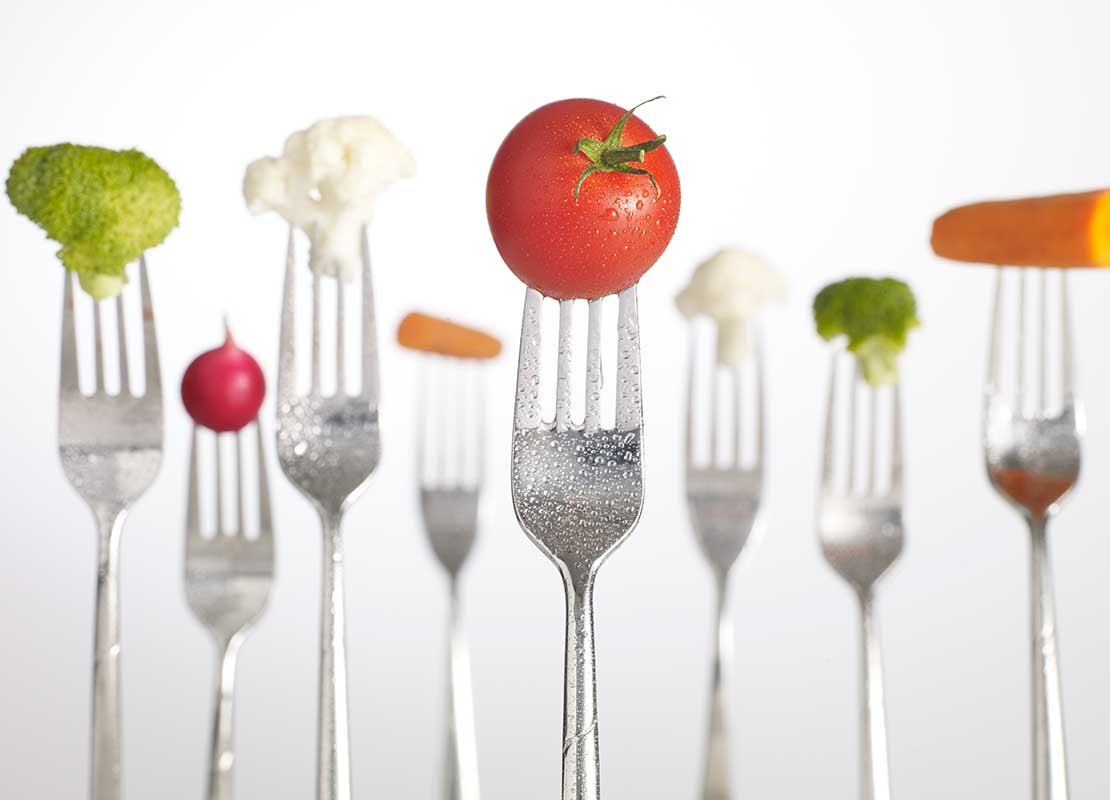 Filas de tenedores de pie sujetan tomates, brócoli, zanahorita, entre otros tipos de verduras