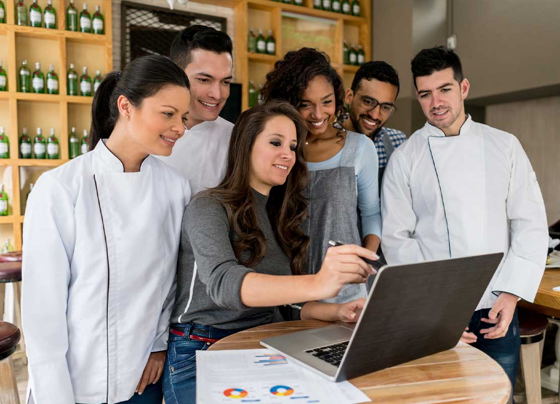 Dueña de un negocio explica a su equipo el uso de un software en un portátil
