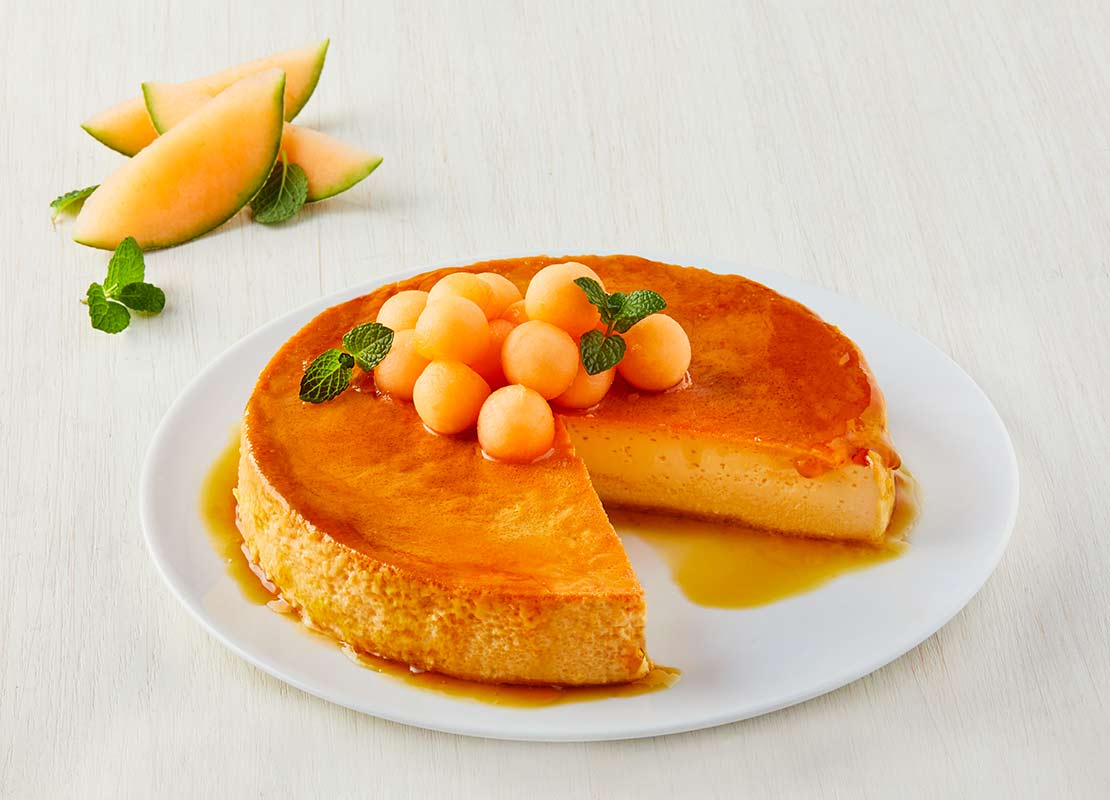 Flan elaborado con leche condensada, huevo y decorado con esferas de melón y hojas de hierbabuena