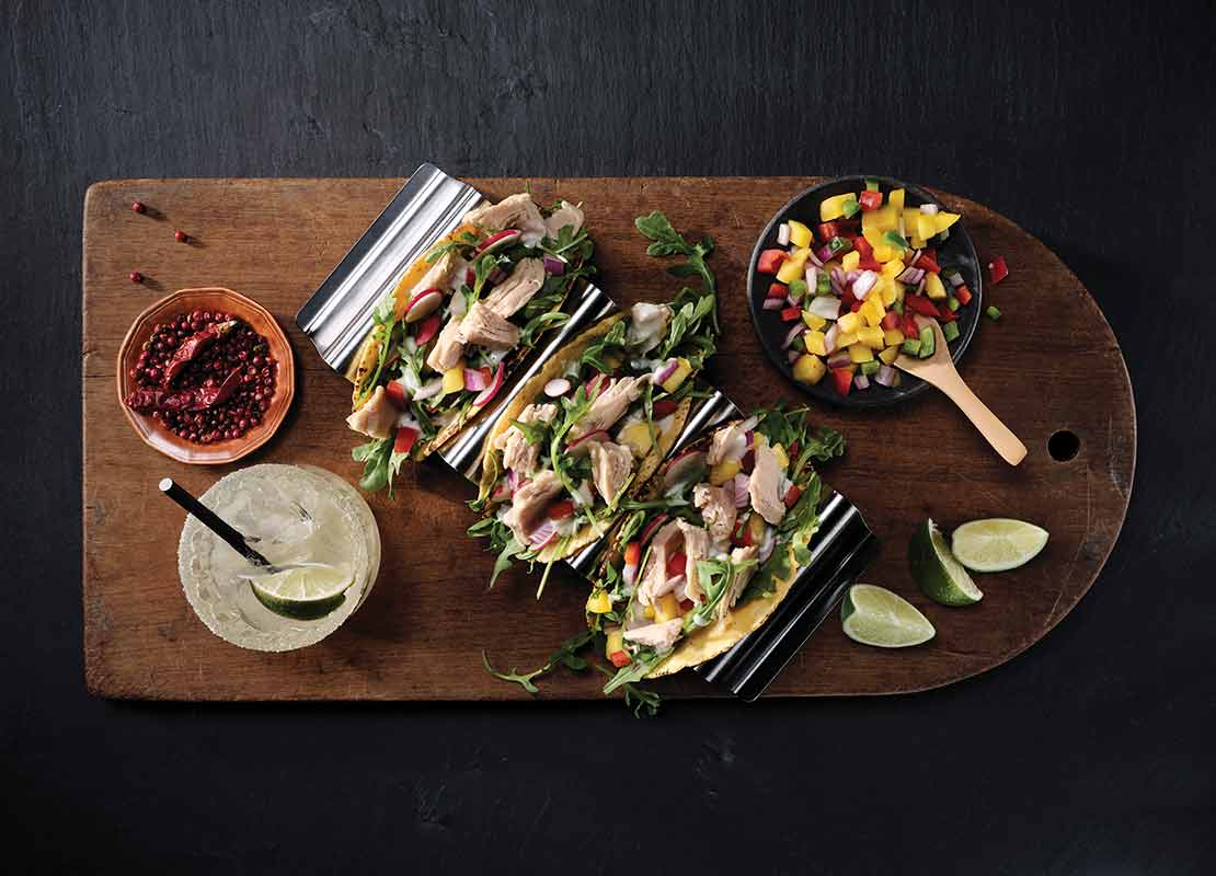 3 tacos de vegetales con pollo servidos a la mesa con limonada y taza de verduras