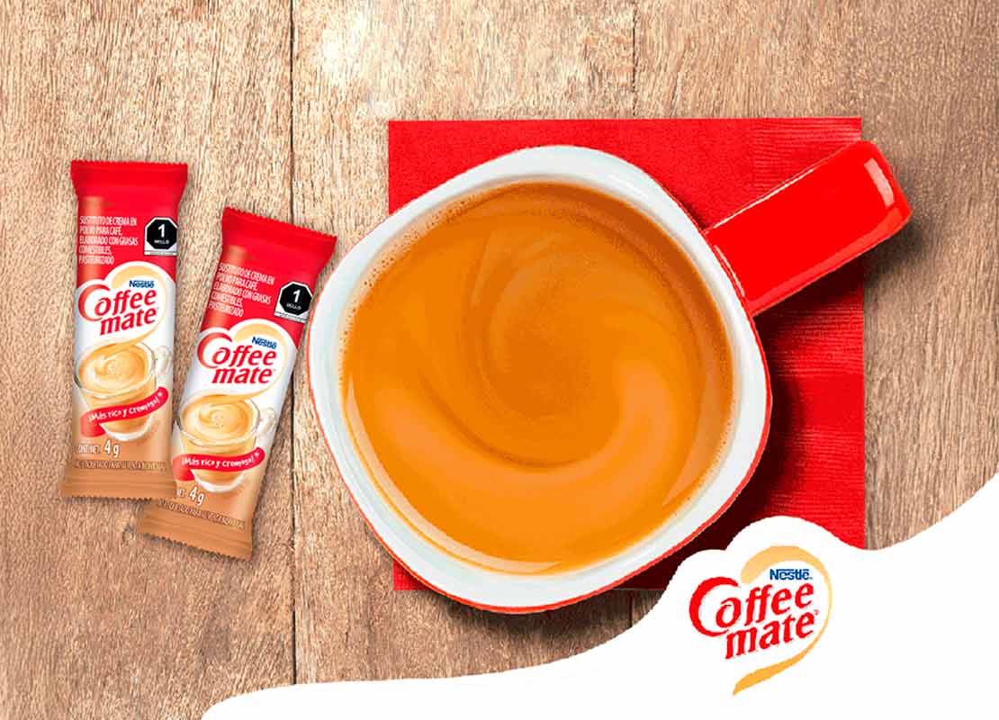 Taza roja de café elaborada con NESCAFÉ y COFFEE MATE®, al lado, sticks de los sustitutos de crema
