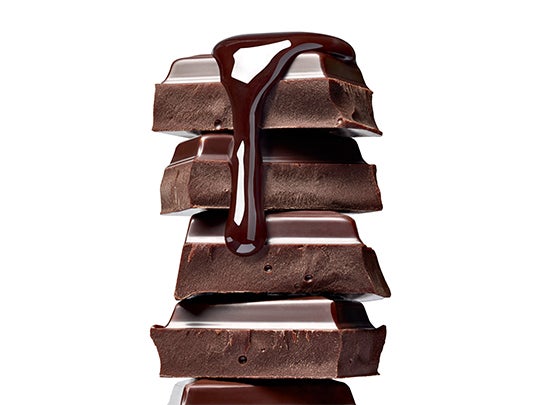 Trozos de barra de chocolate para repostería, puesto uno sobre otro con chocolate derretido encima.