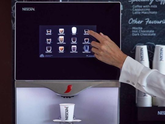 La mano de una mujer utilizando la pantalla táctil de una máquina NESCAFÉ® para hacer café