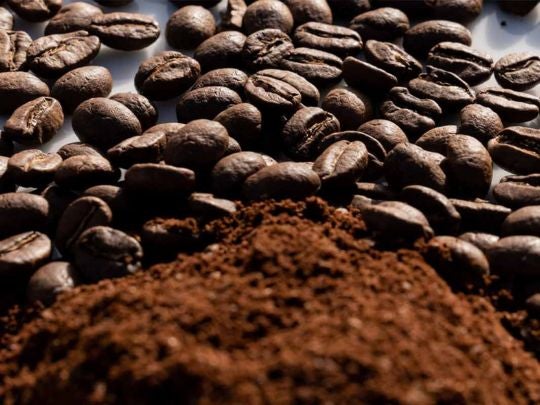 Granos de café y café molido agrupados sobre una mesa de cafetería