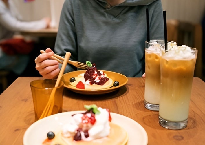 Mujer sentada frente a un postre de frutos rojos y dos frappés servidos