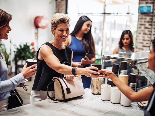 Personas reciben vasos desechables de café en un mostrador de una tienda de conveniencia
