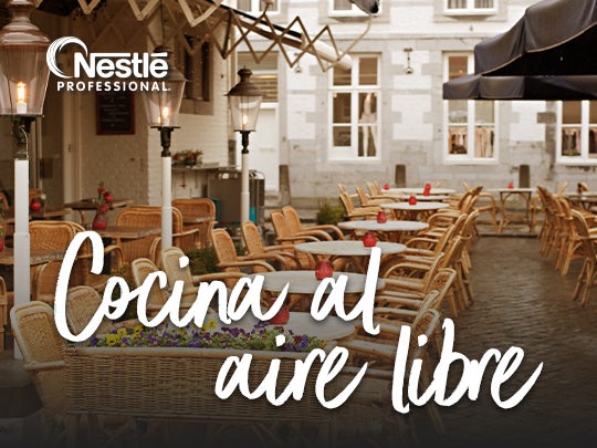 Espacio exterior con mesas preparado para atender clientes en un ambiente de cocina al aire libre.