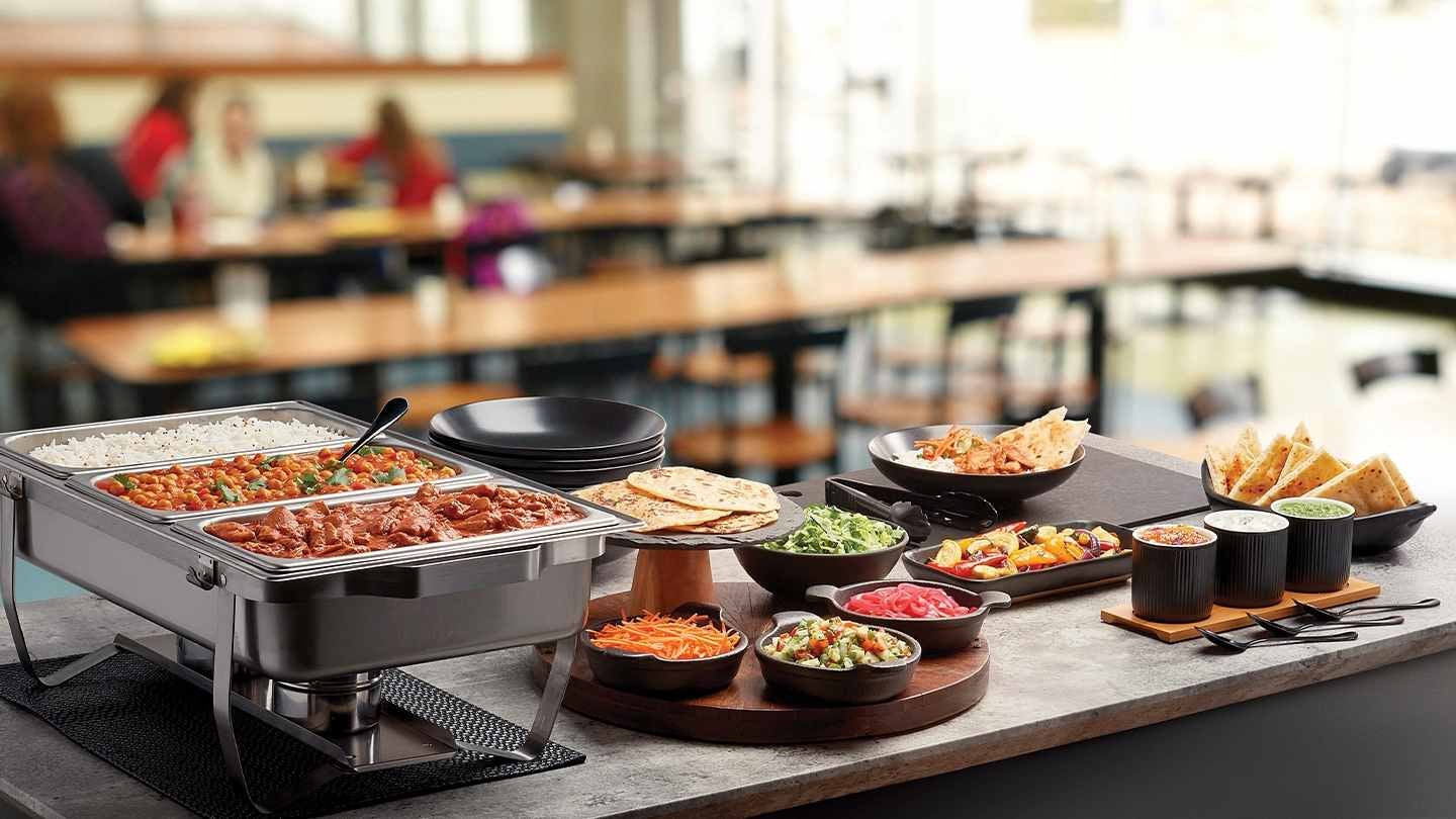 Una food station con diferentes platos, guarniciones y salsas donde los comensales pueden sirvir su comida.