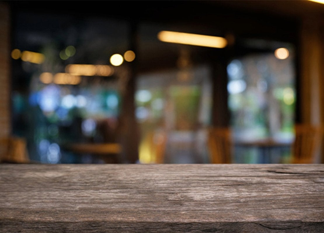 Superficie de mesa rústica con fondo desenfocado de iluminación para restaurante cálida