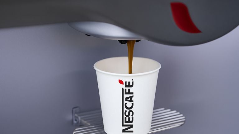 Vaso de NESCAFÉ® llenándose de café recién preparado desde una máquina