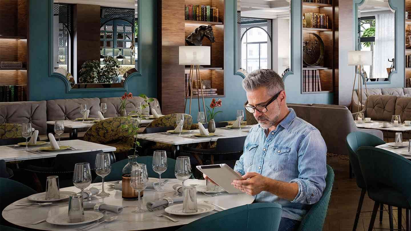 Persona revisa información en tablet dentro de un restaurante para hacer un comparativo de precios.