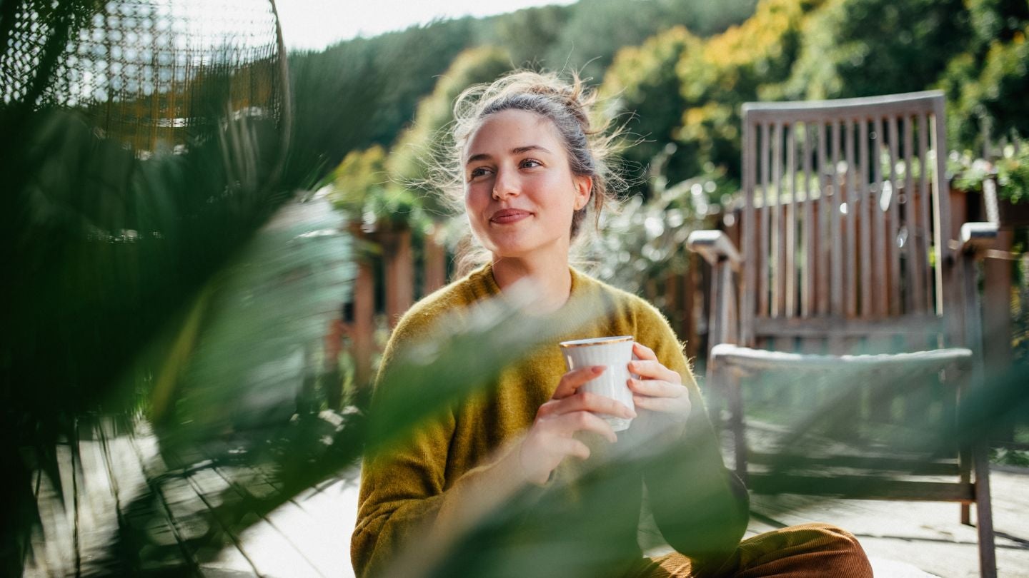 Persona disfrutando una degustación de café en un espacio al aire libre de un negocio gastronómico.