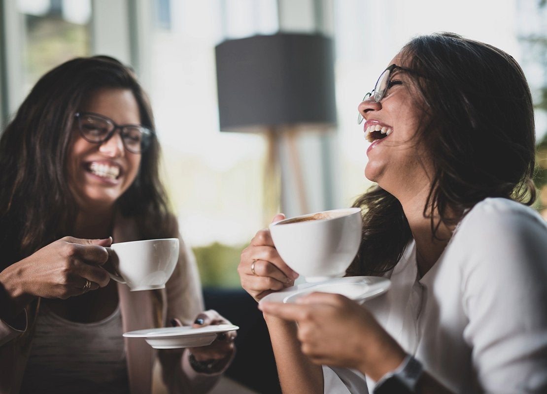 Dos jóvenes beben café y conversan, reflejando distintos tipos de consumidores en cafeterías.