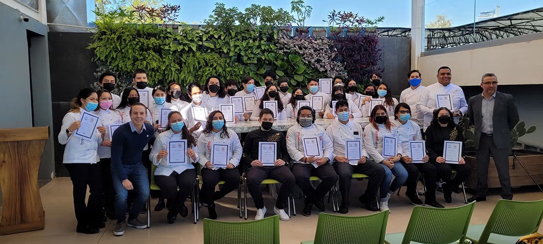 Grupo de estudiantes certificados en barismo mostrando diplomas en una ceremonia