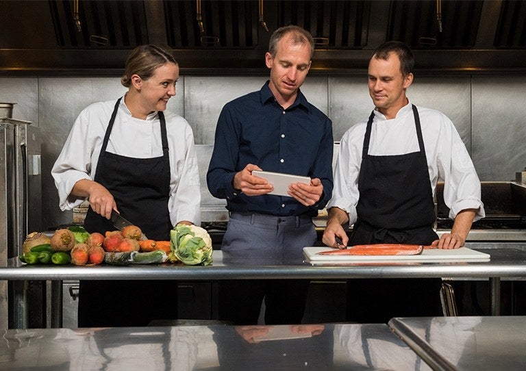 Equipo de chefs analizando recetas y procesos en una cocina profesional
