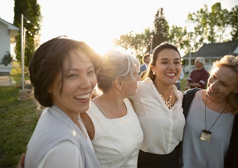Grupo de mujeres abrazadas sonriendo al aire libre durante una actividad comunitaria
