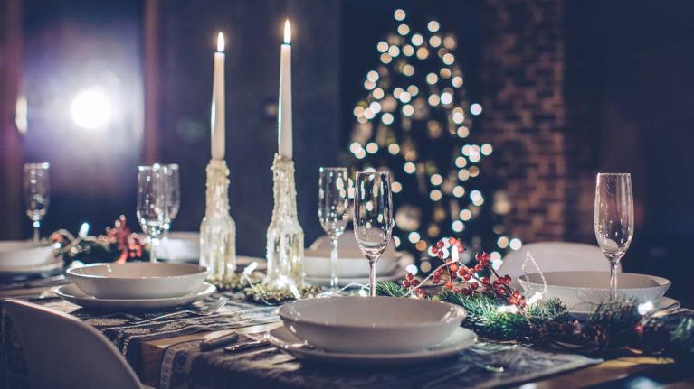 Cena para Navidad con copas de vino, velas y árbol