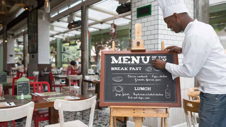 Chef escribe un menú de restaurante a las afueras de su negocio