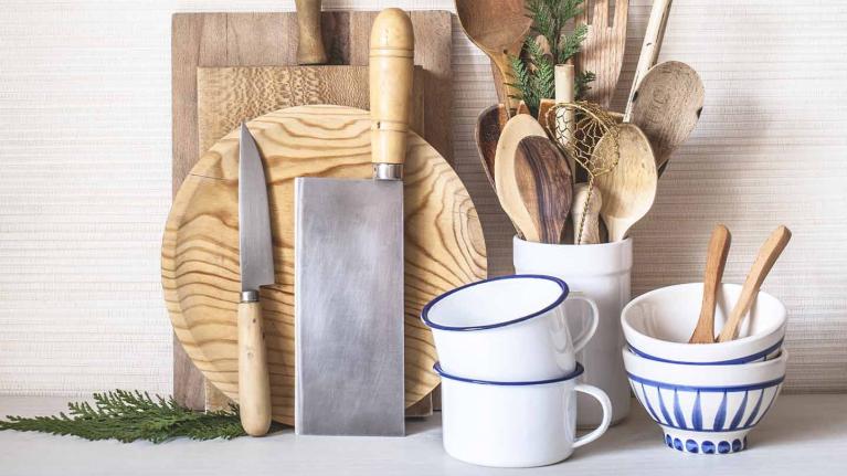 Utensilios de cocina en madera como diversas tablas de picar, cuchillos, cucharas, mezcladores, espátulas, tazas y pocillos