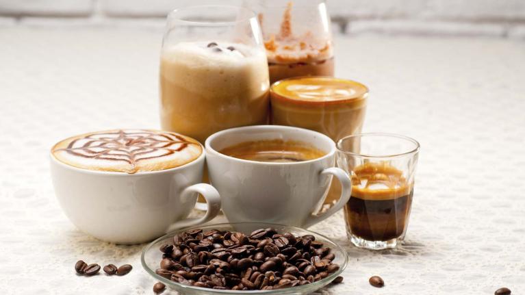 Granos de café tostados y 6 bebidas en diversos tipos de tazas como espresso, café frío, americano, entre otros