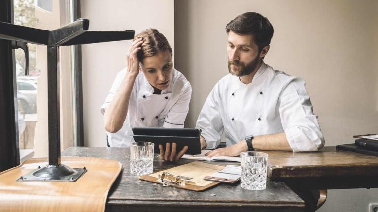 Dos administradores de restaurantes revisan una Tablet en una oficina frente a un escritorio