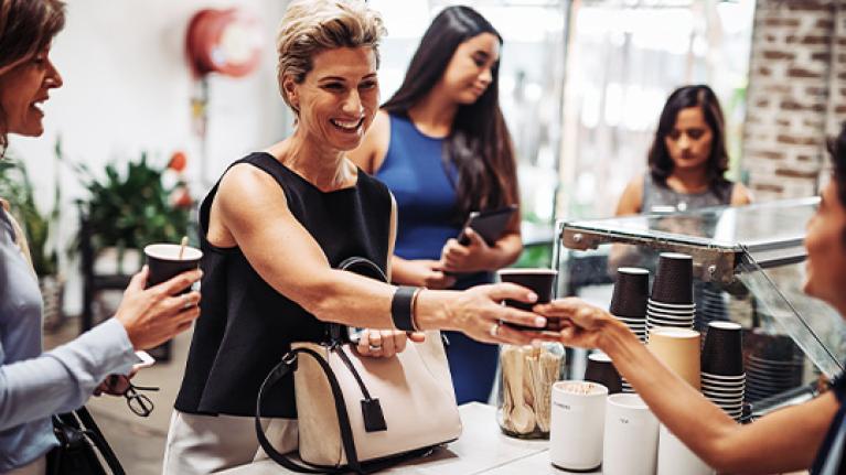 Personas reciben vasos desechables de café en un mostrador de una tienda de conveniencia