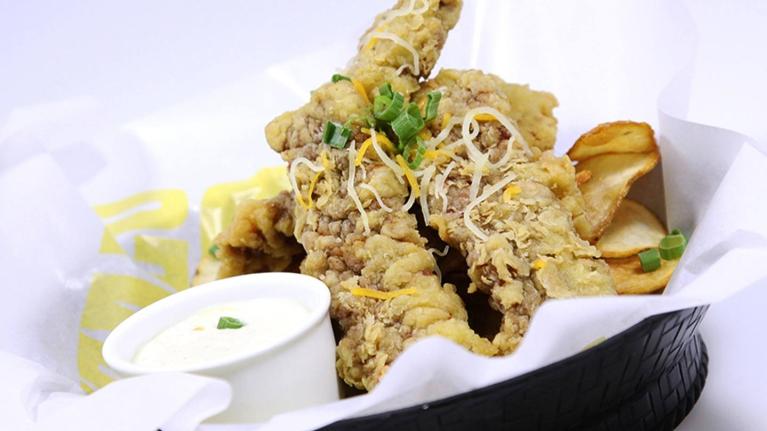 Un canasto con tiras de pollo empanizadas y salsa dip, ideal para un menú fácil y rápido.