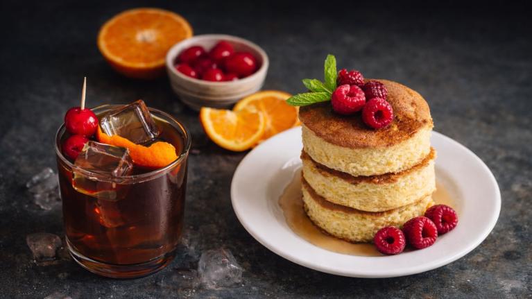 Café frío con cítricos, pancakes con frambuesas y frutas frescas propuesta de menú de temporada