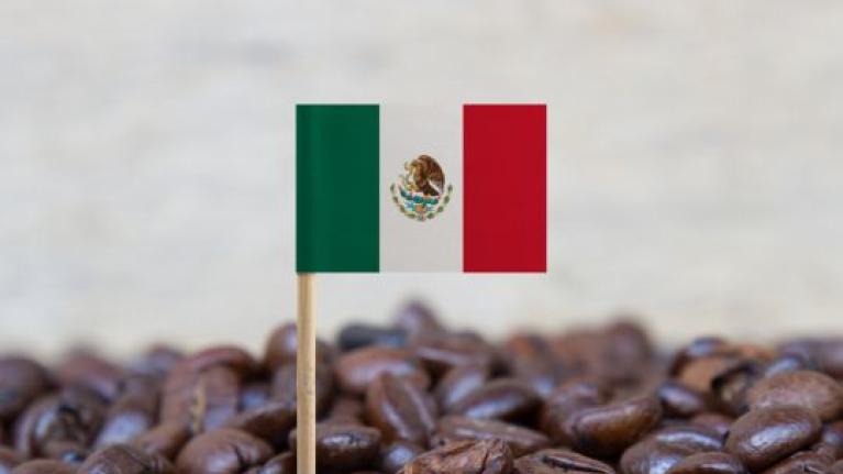 Bandera de México sobre granos de café tostado, representando origen y calidad del producto