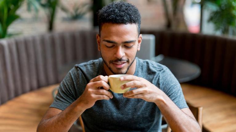 Cliente disfruta una taza caliente explorando sabores de café en un entorno de cafetería. 