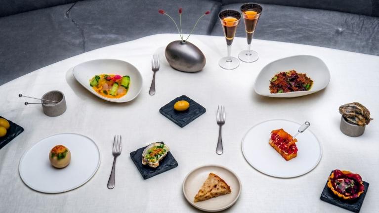 Varios platillos gourmet servidos sobre una mesa con mantel blanco y dos copas de vino fino.