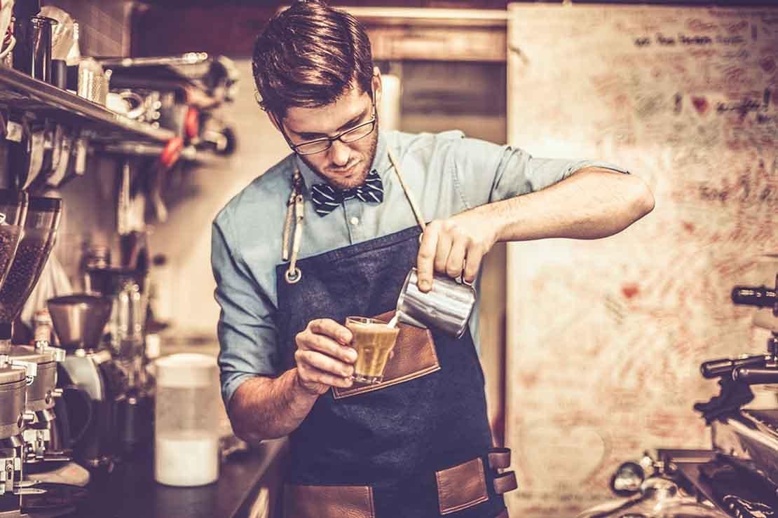 Experto en café prepara en una cafetería una bebida usando latte art, el cual aprendió en Nestlé Jóvenes Baristas