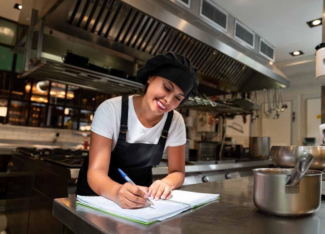 Una chef escribe las descripciones de los platos para el menú de restaurante