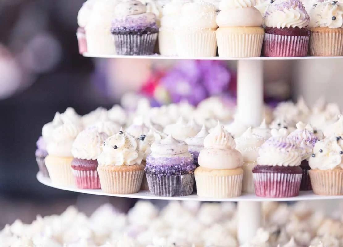 Estructura de varios niveles con cupcakes diferentes que hacen parte de una mesa de postres