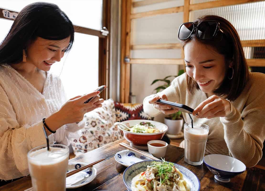 Dos influencers gastronómicas en un restaurante toman fotos de platillos recién servidos para crear contenido