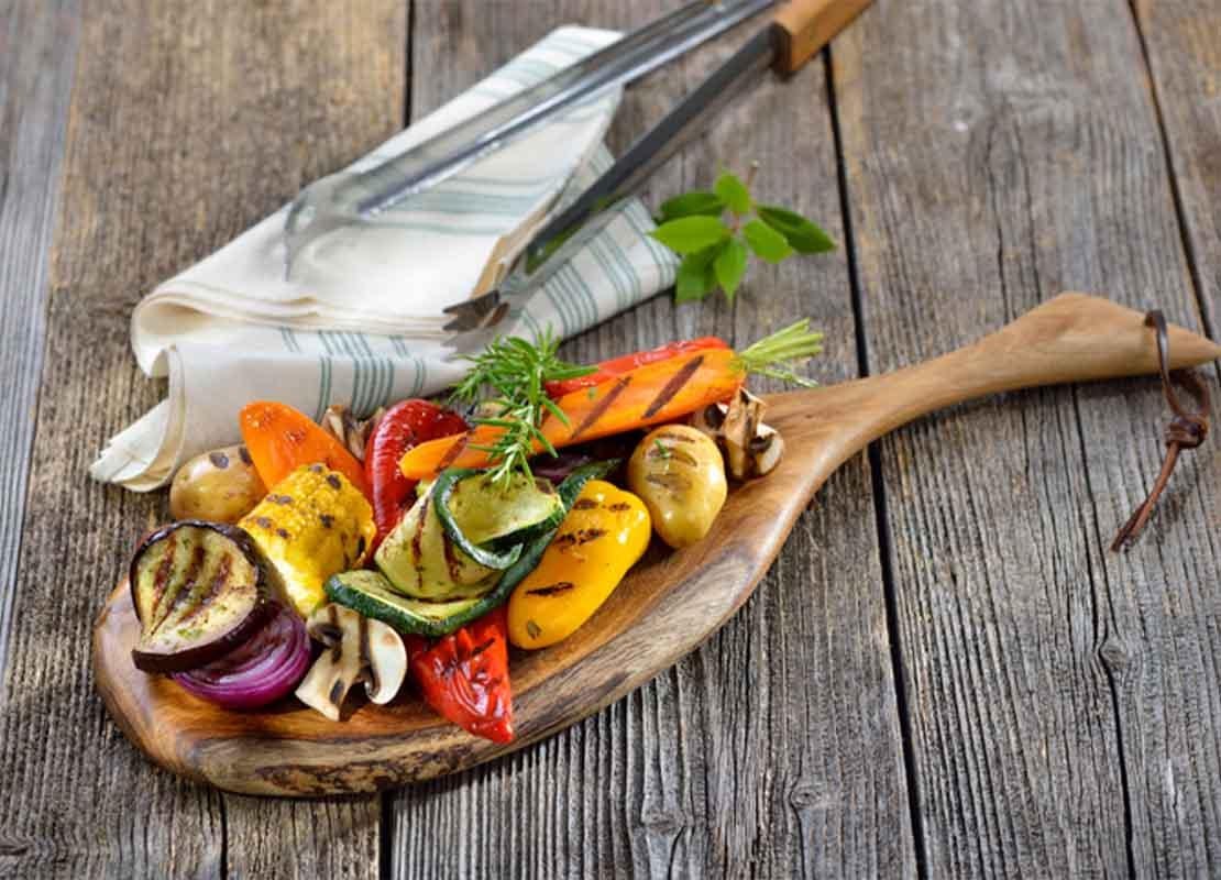 Ingredientes umami como verduras mixtas y hongos shiitake a la parrilla sobre una tabla de cortar