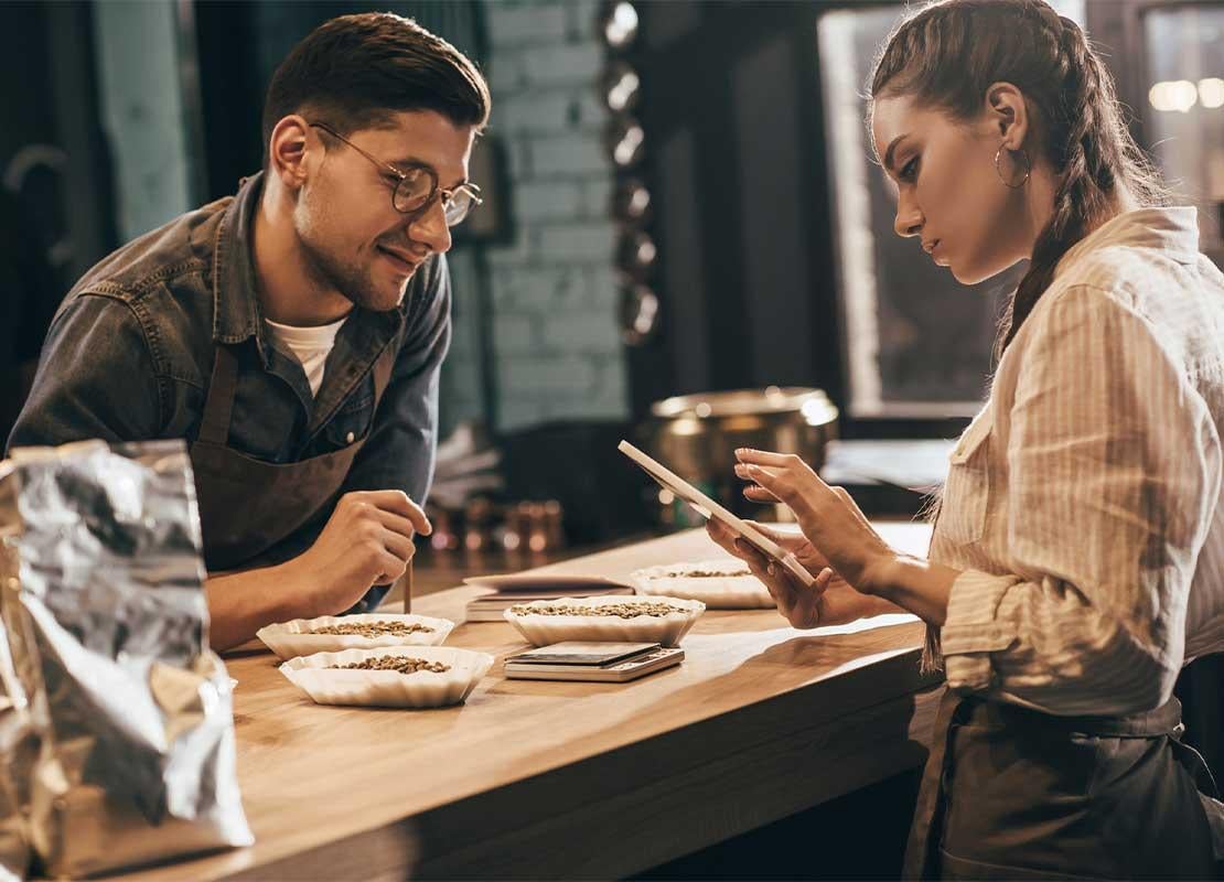 Meseros en la barra de una cafetería revisan las cifras del negocio en una tablet