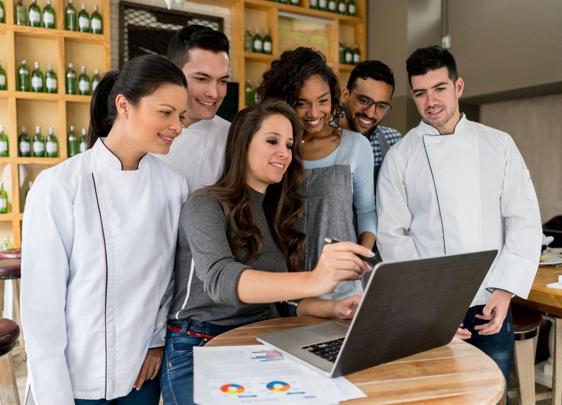 Equipo de trabajo de un bar observa en una laptop estrategias de reducción de costos