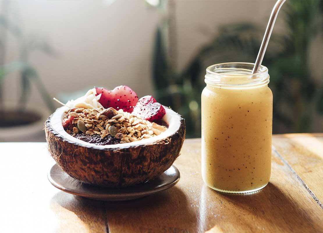 Cascarón de un coco con frutas y granola y batido de mango en una mesa para un brunch