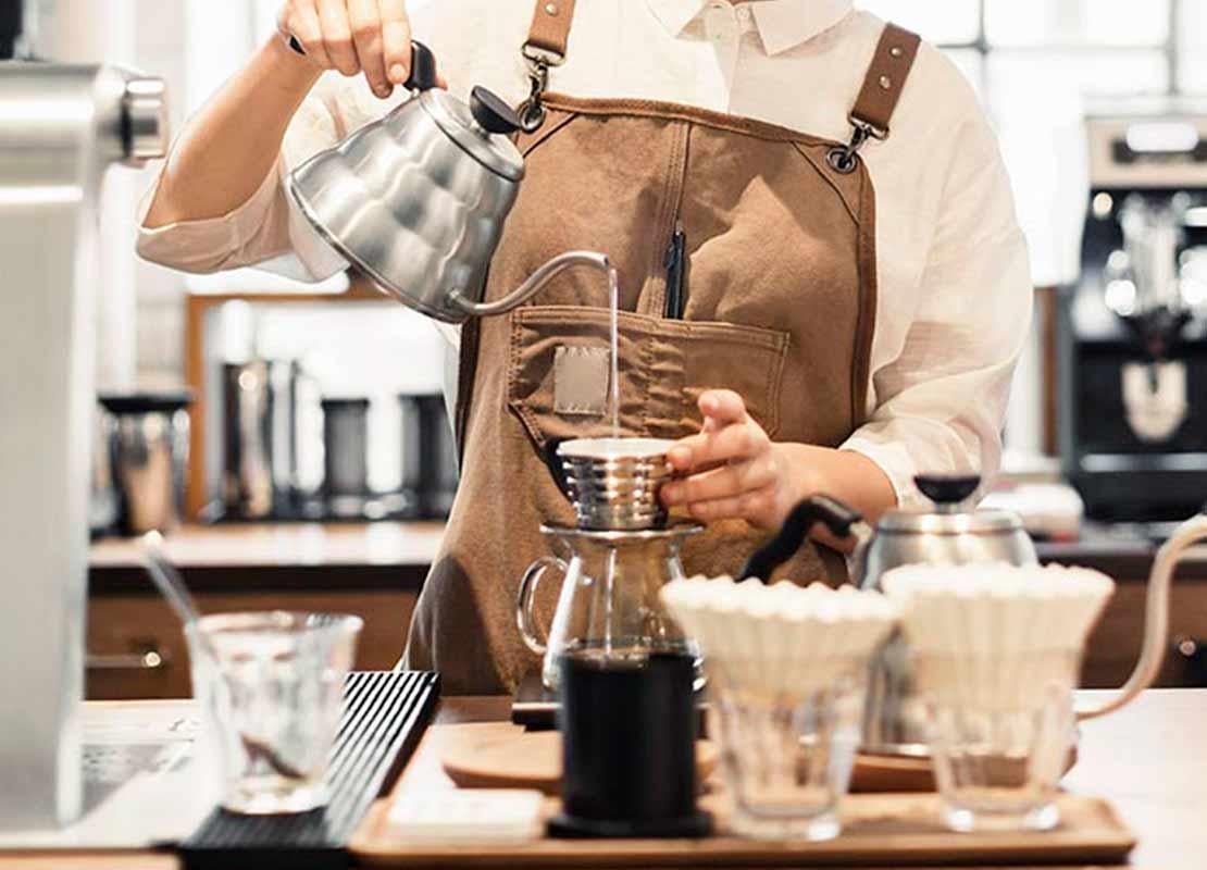 Barista vierte agua caliente sobre un dripper y aplica el método de preparación de café por goteo